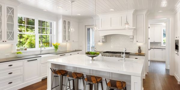 Kitchen with white cabinets and a white kitchen island with four wood and steel chairs. 