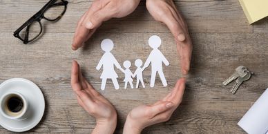 Parent and child's hands forming a circle around paper cut outs of 2 adult & 2 child stick figures