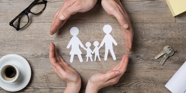 Paper cutouts of a family circled by parent's hands