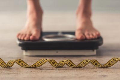 A person checking their body weight on a pair of scales.