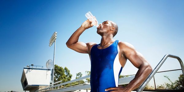 muscular athletic healthy black African American man drinking water in Baltimore Ravens stadium