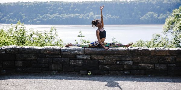 a woman sitting on the wall edge and practicing yoga 