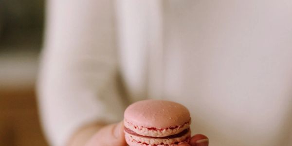 A woman holding a piece of macarons