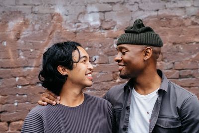 A picture of a male couple. They are looking at each other and smiling.