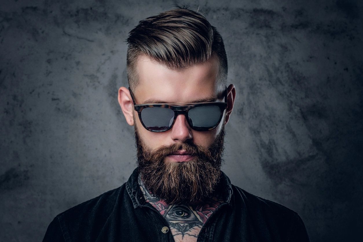 A man wearing custom sunglasses with a black background.