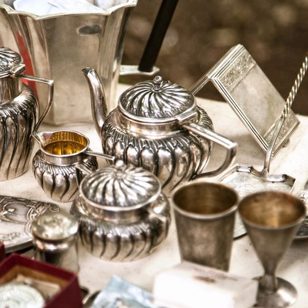 A close up of estate sale items for sale. Silver tea set and other silver plate decor items. 