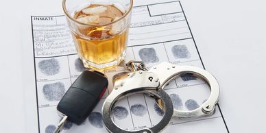 Car keys, handcuffs and alcoholic drink on police station report for arrests  