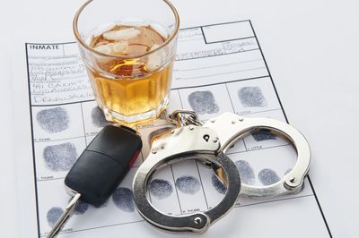 Handcuffs, keys, and an alcoholic beverage on a fingerprint card following a first DUI arrest in Flo