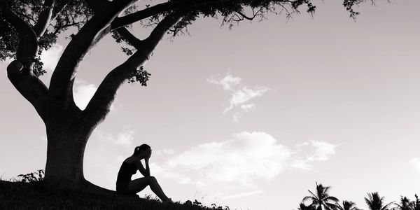 Woman with depression sitting under a tree