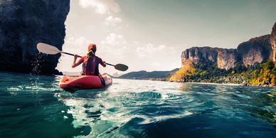 A woman enjoys a kayak trip on a lake surrounded by cliffs