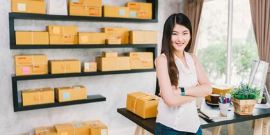 Small Business owner standing in front of boxes of inventory ready to ship