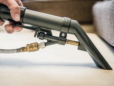 A professional vacuuming a carpet surface