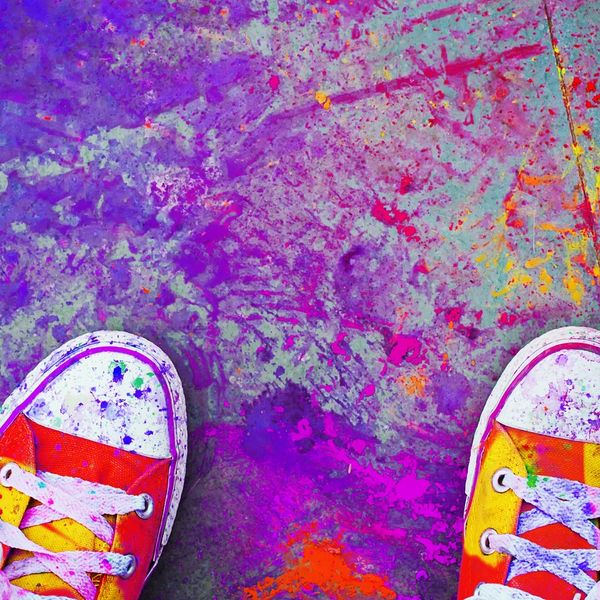 Colorful sneakers and floor splashed with paint.