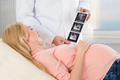 ultrasonographer showing an image to a pregnant client, who is looking at the images 