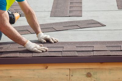 Image of a construction worker installing new shingles onto a roof