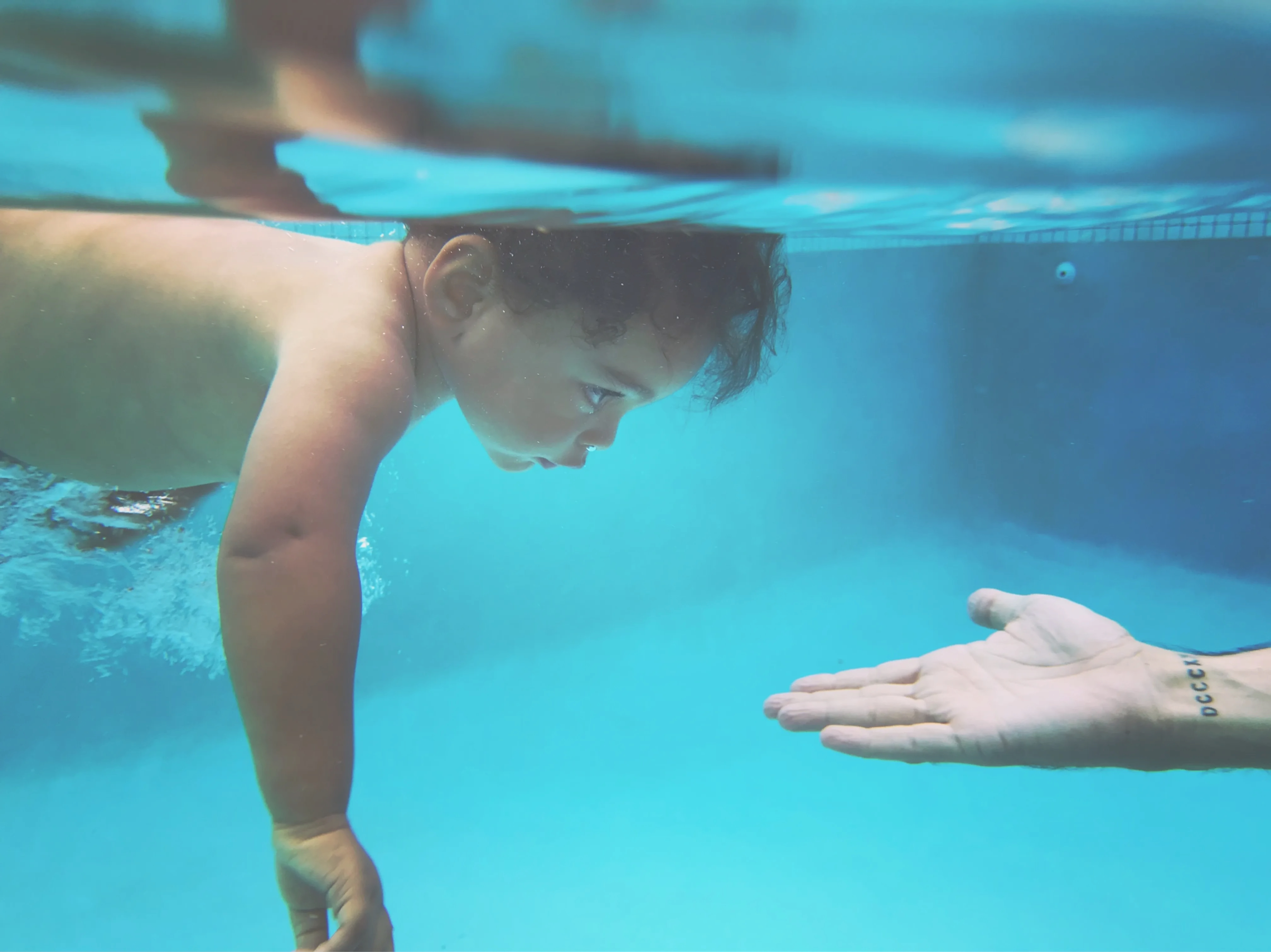 Connection — a child reaching toward a helping hand underwater