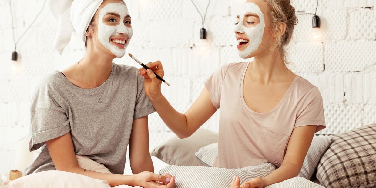 Two women enjoying a facial mask session together, smiling and relaxed.