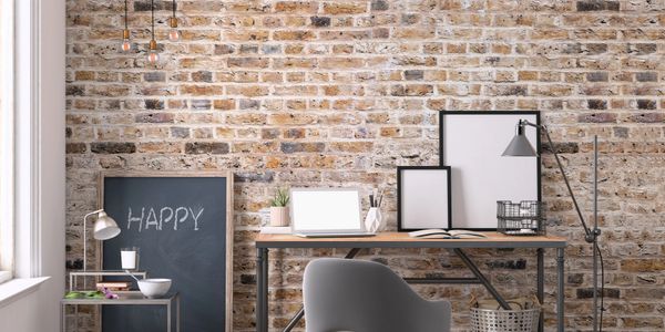 Cozy workspace with brick wall, desk, and 'HAPPY' chalkboard.