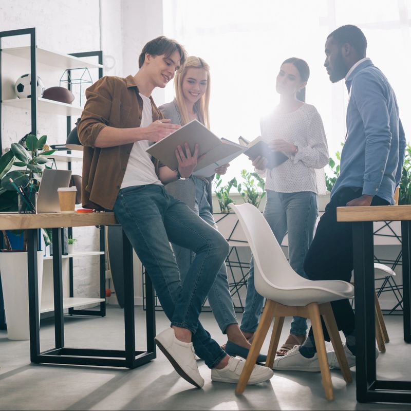 smiling multiethnic businesspeople and textbooks having discussion in modern office