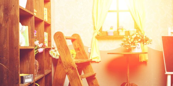 Cozy sunlit room with wooden furniture and flowers.