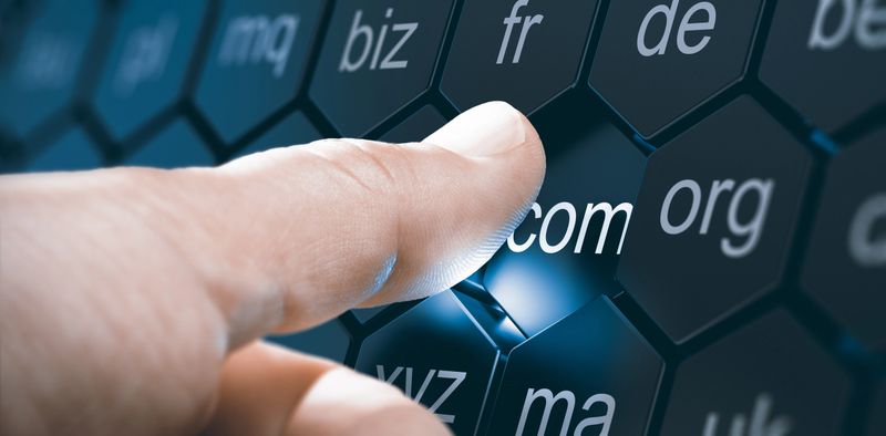 Man selecting a domain extention by pressing an hexagonal button. Composite image between a hand photography and a 3D background.