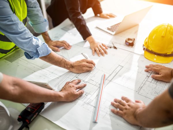 Engineers discussing and marking blueprints at a construction planning meeting.