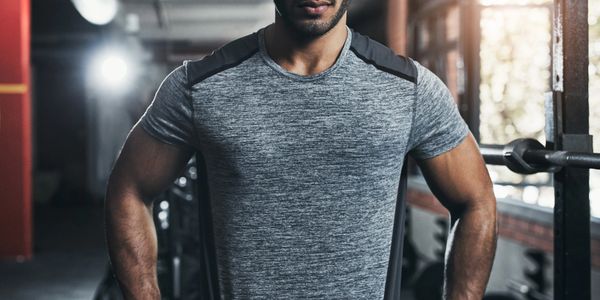 Confident man in gym wear standing with hands on hips indoors.
