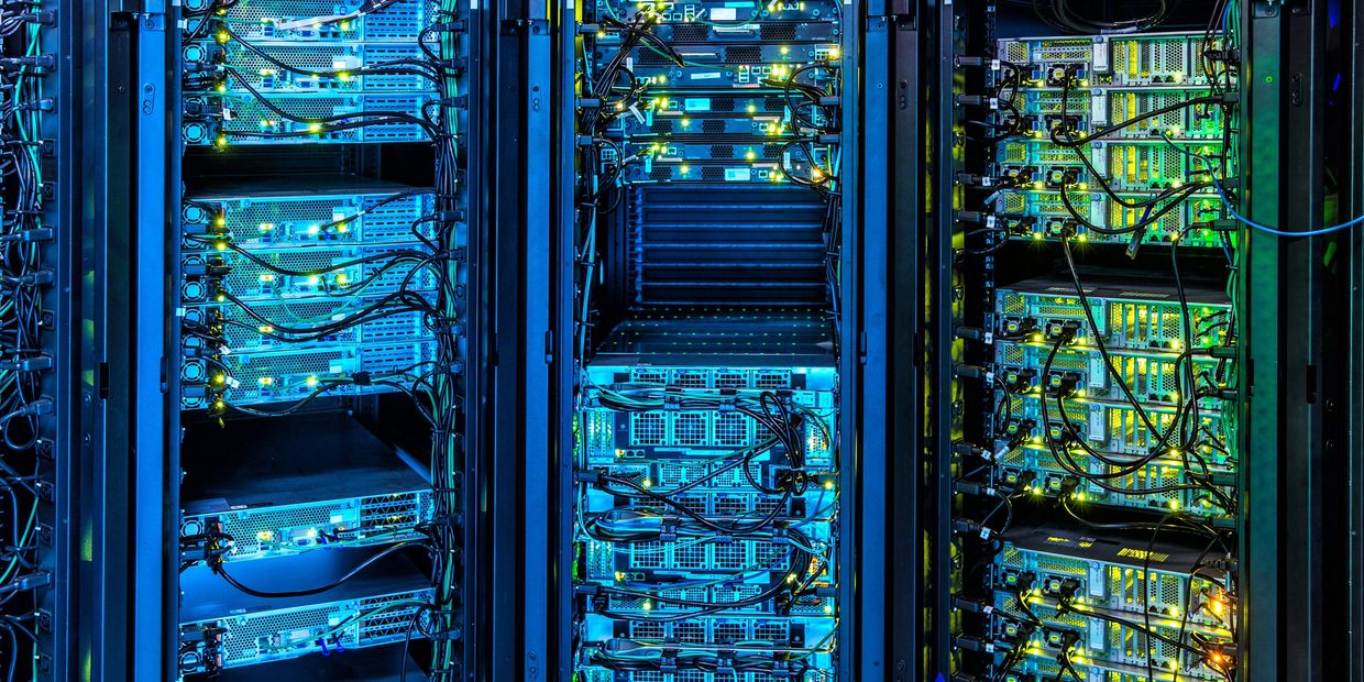 Rows of illuminated server racks with networking cables in a data center.