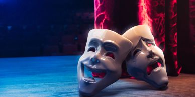Comedy and tragedy masks on stage floor.