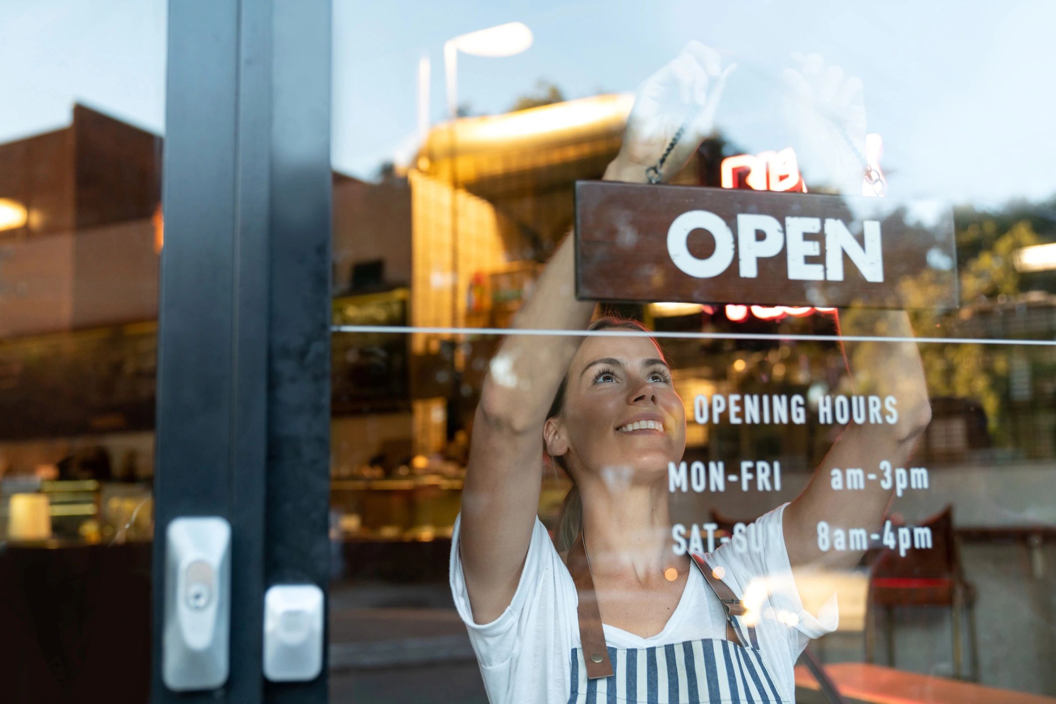 Small business owner putting up an open sign in their window.