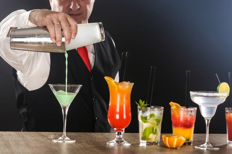Adult bartender pouring liquer from shaker, preparing various cocktails - Cosmopolitan, Bloody Mary etc. About 40 years old, Caucasian man.