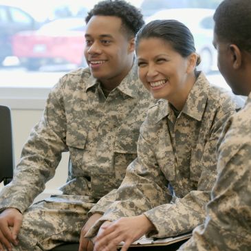 Soldiers in camouflage uniforms smiling and talking.