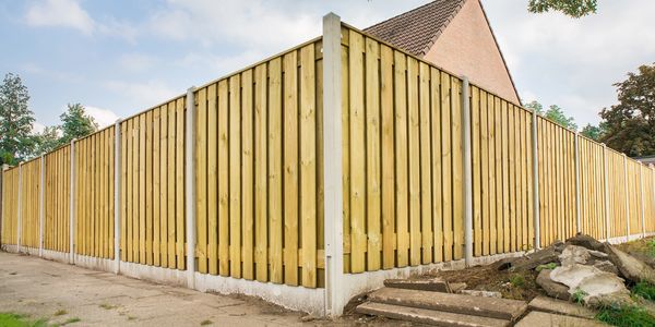 Newly installed wooden fence around a residential property under a clear sky.