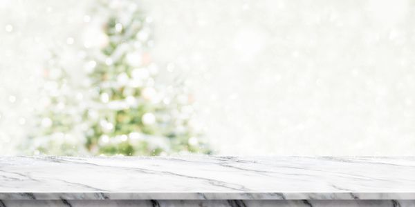 Marble surface with blurred Christmas tree and snow background.