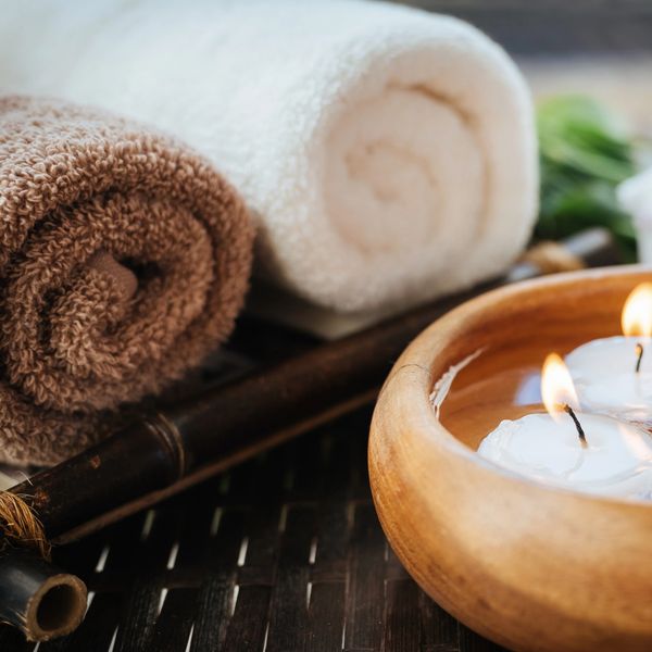 Spa towels and floating candles in a wooden bowl 