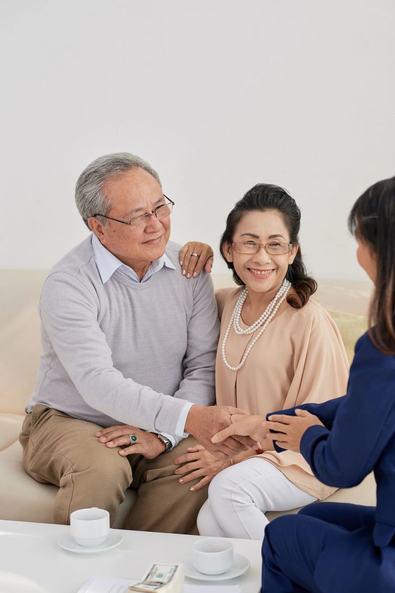 Cheerful senior couple shaking hand of financial manager after consulting session