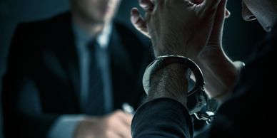 Person in handcuffs being interrogated by a man in a suit.