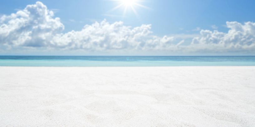 Sunny beach with white sand and blue ocean.