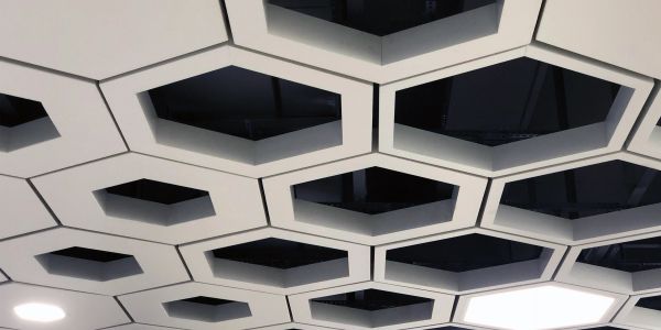 Ceiling with hexagonal recessed panels, one illuminated.