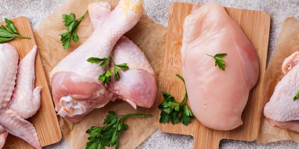 Raw chicken pieces with parsley on cutting boards.