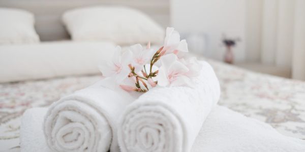 Rolled white towels with flowers on a bed.