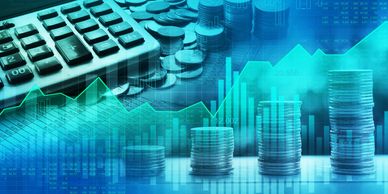 Stacks of coins with a calculator and financial charts.