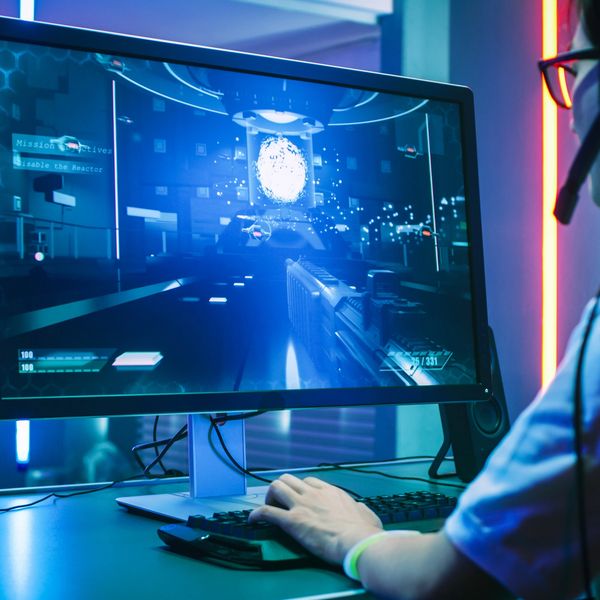 Person playing a futuristic first-person shooter game on a high-resolution monitor.