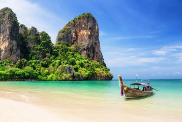 Boat near tropical beach with cliffs.