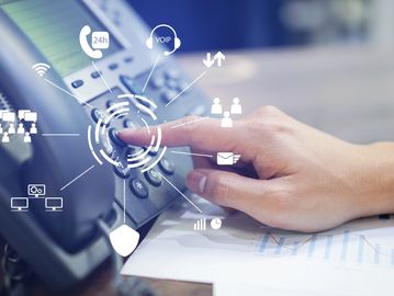 Hand dialing a phone surrounded by communication icons symbolizing connectivity and network technology.