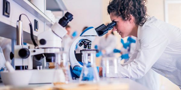 Scientist examining samples with a microscope in a laboratory.