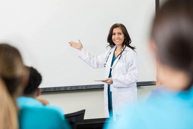 Female doctor giving a presentation to an audience in a classroom.