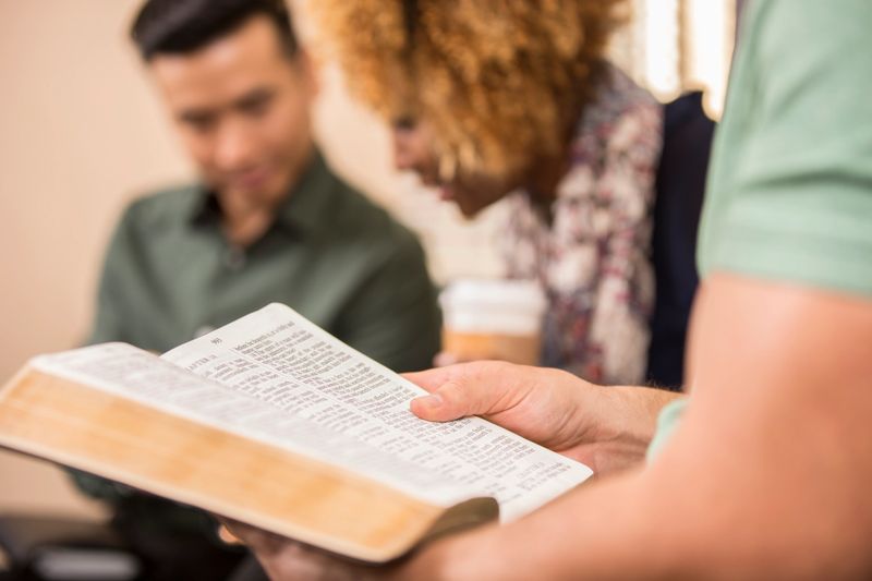 Multi-ethnic, mixed age group of people involved in Christian bible study meeting at local church.