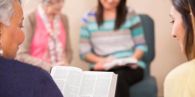 A group of women reading and sharing from a Bible in a small group setting.