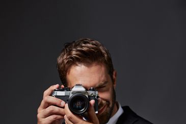 Man holding a vintage camera and smiling.